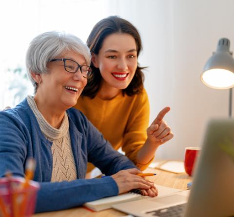 Une mère et sa fille majeure discutent et regardent l'ordinateur sur le bureau. 