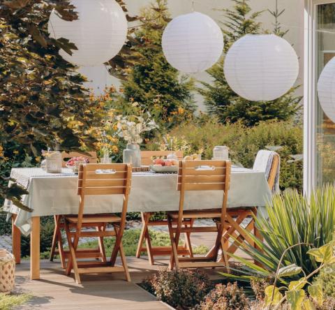 Vue sur une terrasse avec table de repas et guirlande lumineuse