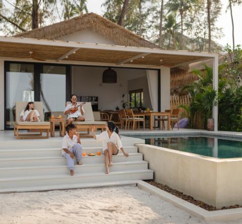 Un couple et ses deux enfants profitent d'une belle villa avec petite terrasse et piscine. 