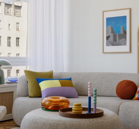 Salon moderne avec un canapé gris et des éléments de déco très colorés. 