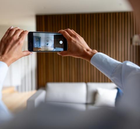 Une femme tourne une vidéo de son appartement avec son téléphone.